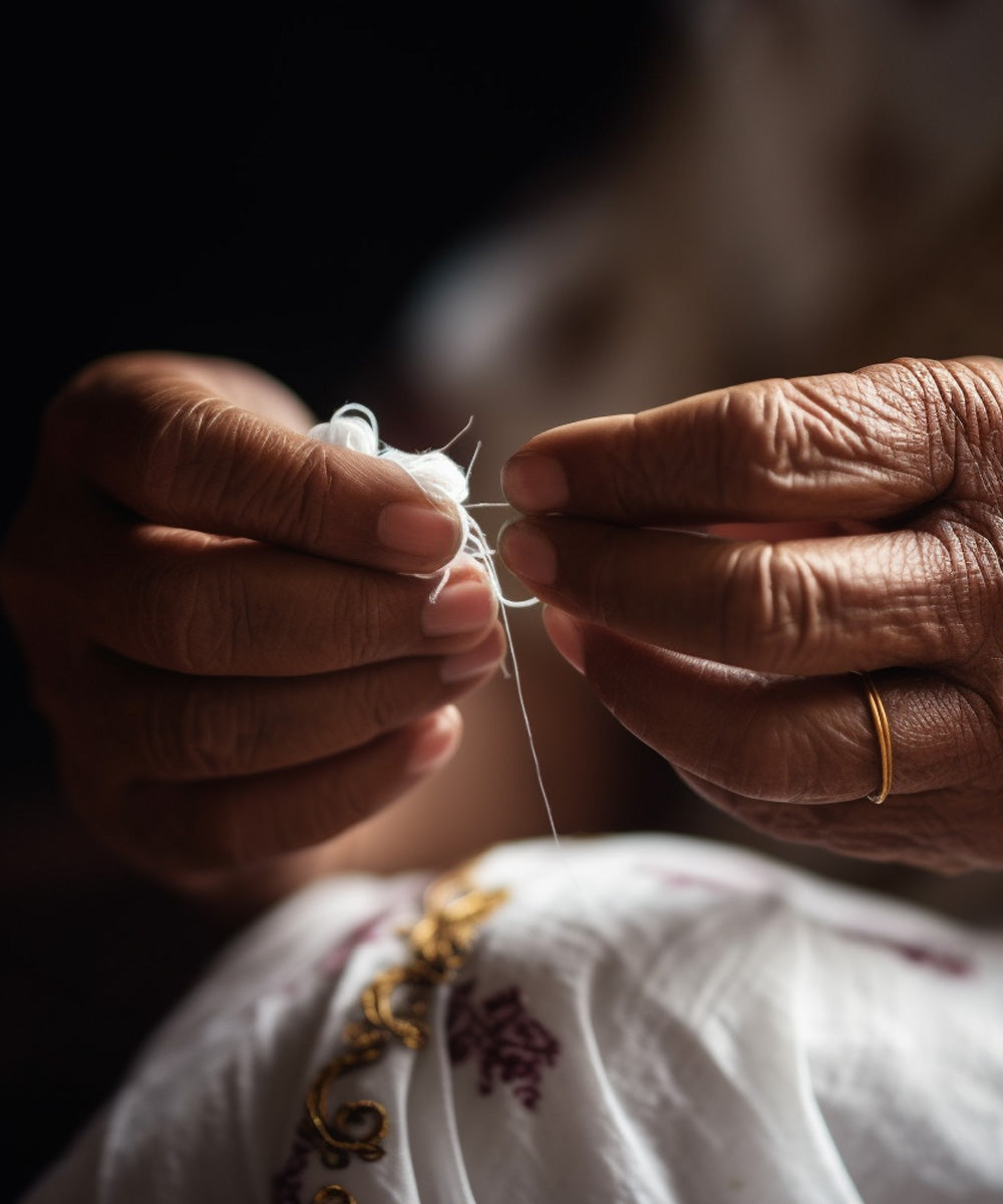 Close up of a Bengali woman's hands working with white thread