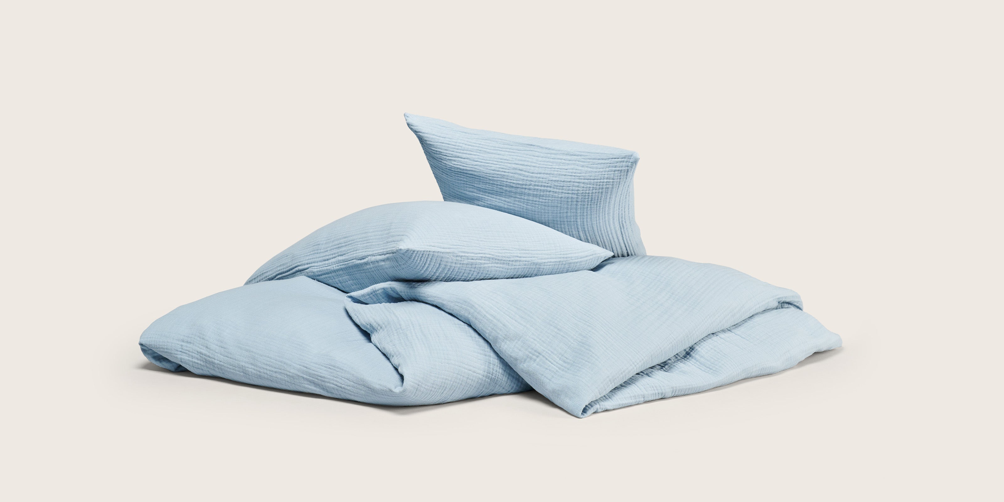 Blue muslin duvet and two pillows in a neat pile 
